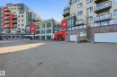 Contemporary multi-story building featuring extensive glazing, red panel accents, and stone-look cladding - 528 5151 Windermere Boulevard, Edmonton, AB 