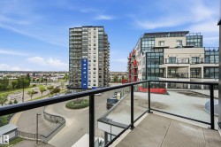 Balcony featuring glass and metal railings, textured surface, and urban surroundings with multi-story buildings and a streetscape - 