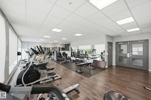 Fitness center featuring wood-finish flooring, a mirrored wall, and recessed ceiling lighting - 528 5151 Windermere Boulevard, Edmonton, AB 