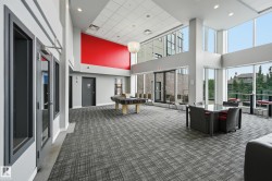 Spacious common area featuring extensive glazing, high ceilings, patterned carpet flooring, and a red accent wall - 