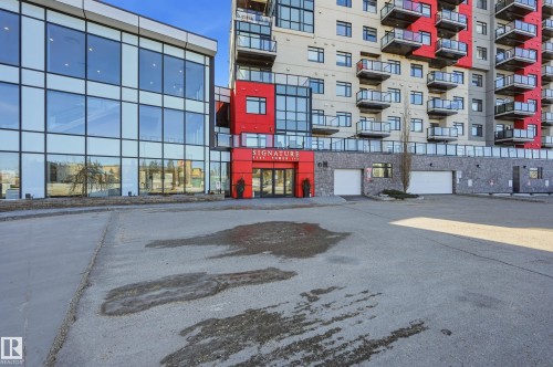 Modern multi-story building featuring a red and grey facade with extensive glass balconies - 528 5151 Windermere Boulevard, Edmonton, AB 