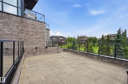 Spacious outdoor patio featuring stone-look pavers and clear glass railings with black frames - 