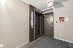 Hallway entry featuring a modern dark wood-finish door, light beige walls, and contemporary wall sconce lighting - 