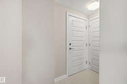 Entryway featuring a white paneled door with brushed nickel hardware, light-toned wall paint, white baseboards, and light tile flooring - 