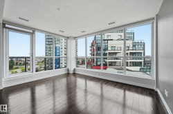 Spacious room featuring extensive window-wall construction, dark wood-finish flooring, a white ceiling with recessed lighting, and light grey painted walls - 