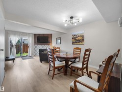 Open-concept living area featuring wood-finish flooring, a contemporary ceiling light fixture, and a fireplace with decorative tile surround - 