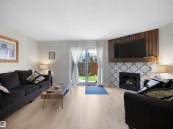 Living area featuring light wood-finish flooring, a decorative fireplace with patterned tile surround, and a wood mantel - 