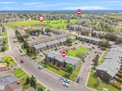 Aerial perspective showcasing a community of townhome-style residences with individual fenced yards, surface parking, and a bordering green space - 