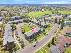 Aerial perspective of a multi-unit property featuring dark siding and light-colored roofing - 