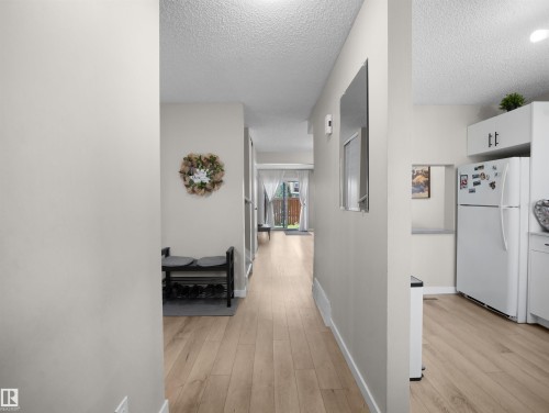 Bright hallway featuring light wood-finish flooring, neutral wall paint, and recessed lighting - 575 Dunluce Road, Edmonton, AB 