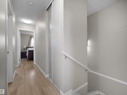 Hallway featuring wood-finish flooring, light neutral paint, and white trim - 