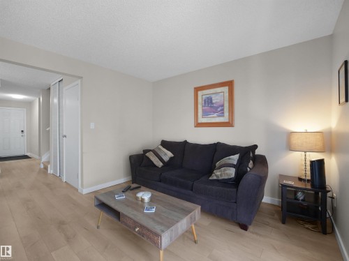 Living area featuring light wood-finish flooring, neutral wall tones, white baseboards, and a white entry door - 575 Dunluce Road, Edmonton, AB 