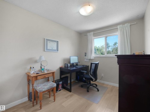 Room featuring light wood-finish flooring, neutral wall tones, and a window with white curtains - 575 Dunluce Road, Edmonton, AB 