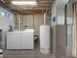 Dedicated utility area featuring a washer and dryer set, a water heater, and mechanical systems - 