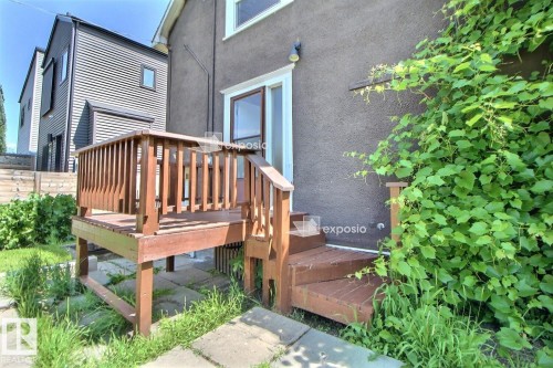 Rear deck with wood railing and steps, featuring a sliding glass patio door - 11312 127 Street, Edmonton, AB 
