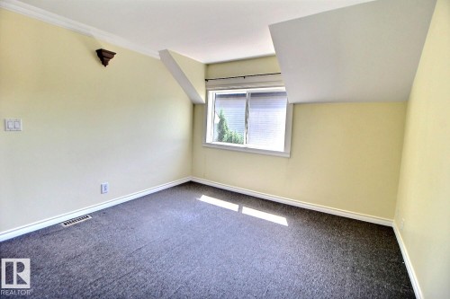 Neutral-toned room featuring dark gray carpeting and light yellow walls - 11312 127 Street, Edmonton, AB 