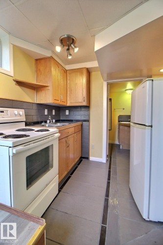 Kitchen featuring wood cabinetry, a white electric range, and a white refrigerator - 11312 127 Street, Edmonton, AB 