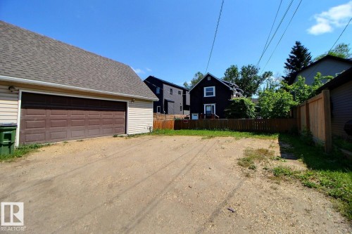 Detached garage featuring horizontal vinyl siding, a brown panel-style garage door, and a shingle roof - 11312 127 Street, Edmonton, AB 