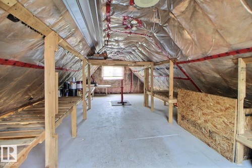 Attic space featuring exposed insulation, concrete flooring, and built-in wooden shelving - 11312 127 Street, Edmonton, AB 