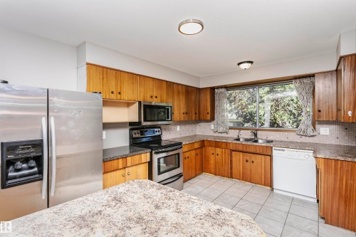 Kitchen featuring wood cabinetry, a stainless steel refrigerator, and a built-in microwave - 11440 44A Avenue, Edmonton, AB 