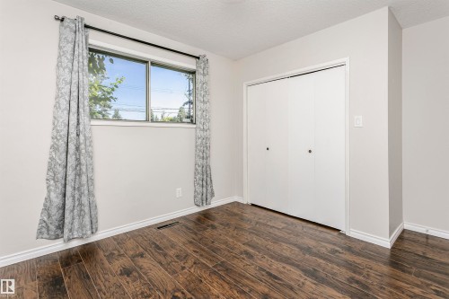 Wood-finish flooring throughout, featuring a double window with a dark rod and white trim - 11440 44A Avenue, Edmonton, AB 