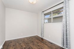Room featuring wood-finish flooring, white baseboards, and neutral wall paint - 