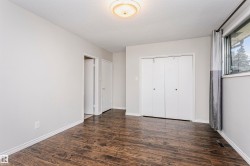 Spacious room featuring wood-finish flooring, light grey wall paint, and a textured ceiling - 