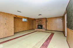 Brick fireplace with hearth, wood paneling throughout, and a recessed window - 