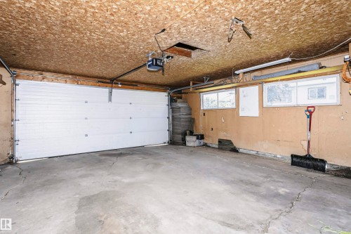 Single-bay garage featuring a concrete floor, three windows, and a built-in garage door opener system - 11440 44A Avenue, Edmonton, AB 