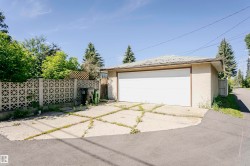 Detached garage with a white overhead door, stucco exterior, and asphalt shingle roof - 