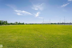 Expansive athletic field with manicured green grass, featuring a set of goalposts and perimeter lighting - 