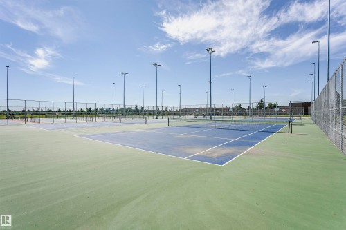 Multiple hard-surface courts featuring blue and green playing areas, perimeter chain-link fencing, and ample overhead lighting fixtures - 11440 44A Avenue, Edmonton, AB 