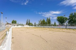 Open-air hard court area with perimeter fencing and tall light poles - 