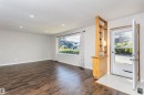 Spacious living area featuring dark wood-finish flooring, recessed ceiling lighting, and a large picture window - 11440 44A Avenue, Edmonton, AB 