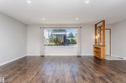 Spacious room featuring wood-finish flooring, recessed lighting, and a large front-facing window - 