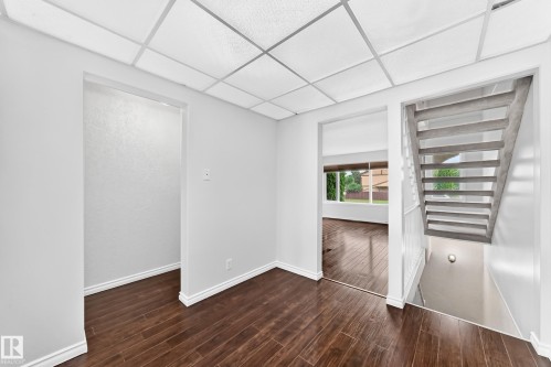 Hardwood-finish flooring extends through multiple rooms and features white baseboards, offering a cohesive aesthetic - 11447 22 Avenue Nw, Edmonton, AB 