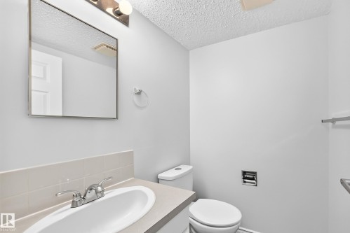Bathroom featuring a vanity with an integrated sink, polished chrome faucet, and a wall-mounted mirror - 11447 22 Avenue Nw, Edmonton, AB 