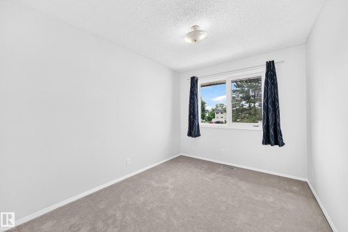 Bright interior space featuring light gray carpeting and white walls - 11447 22 Avenue Nw, Edmonton, AB 