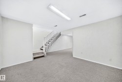 Carpeted room featuring a staircase with white railing, recessed lighting, and white baseboards - 