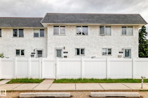 Multi-unit building featuring white textured stucco exterior and a dark shingle roof - 11447 22 Avenue Nw, Edmonton, AB 