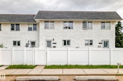 Multi-unit building featuring white textured stucco exterior and a dark shingle roof - 