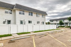 Multi-unit residential building featuring a textured white exterior, contrasting dark shingle roof, and white-framed windows - 
