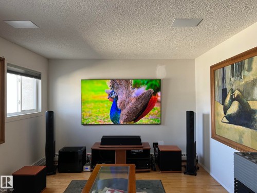 Living space featuring light wood-finish flooring, a wall-mounted display, and built-in ceiling speakers - 207 18012 95 Avenue, Edmonton, AB - Indoor