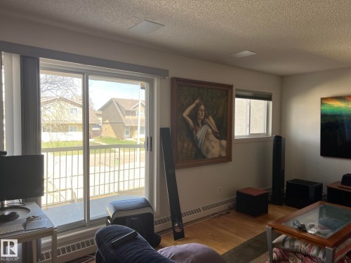 Expansive sliding glass doors open to an outdoor balcony with metal railings - 207 18012 95 Avenue, Edmonton, AB - Indoor Photo Showing Living Room