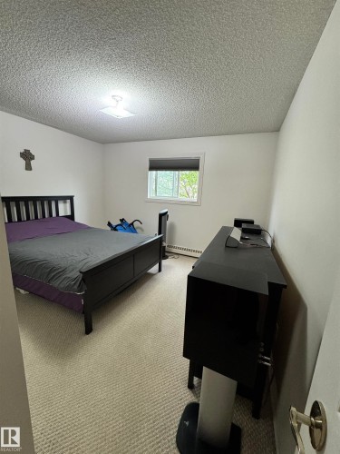 Carpeted room with a textured ceiling and a central flush-mount light fixture - 207 18012 95 Avenue, Edmonton, AB 