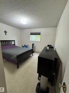 Carpeted room with a textured ceiling and a central flush-mount light fixture - 