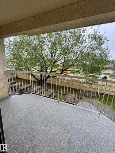 Balcony featuring a speckled gray surface, light-colored railing, and a textured ceiling - 207 18012 95 Avenue, Edmonton, AB 
