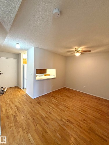 Light wood-finish flooring extends through the main living area - 207 18012 95 Avenue, Edmonton, AB 