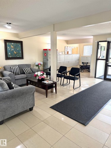 Lobby area featuring light-toned tile flooring, recessed lighting, and a mail center with individual mailboxes - 207 18012 95 Avenue, Edmonton, AB 