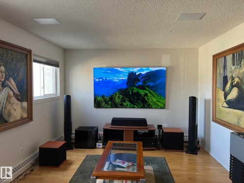 Living area featuring wood-finish flooring, a wall-mounted display, and recessed ceiling speakers - 207 18012 95 Avenue, Edmonton, AB - Indoor